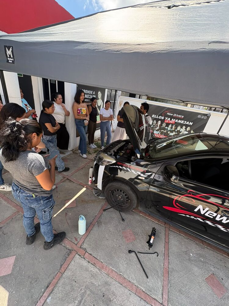 Instructor de New Drivers mostrando a un grupo de alumnas cómo cambiar una llanta